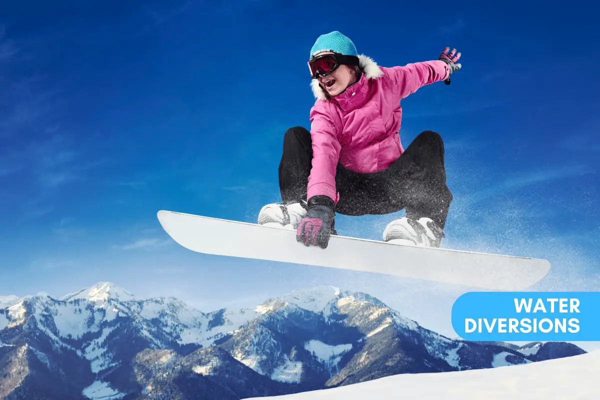 Woman getting air on a snowboard in front of a camera